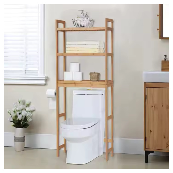 Bamboo bathroom storage rack with three shelves, positioned above a toilet, holding towels, toilet paper, and toiletries