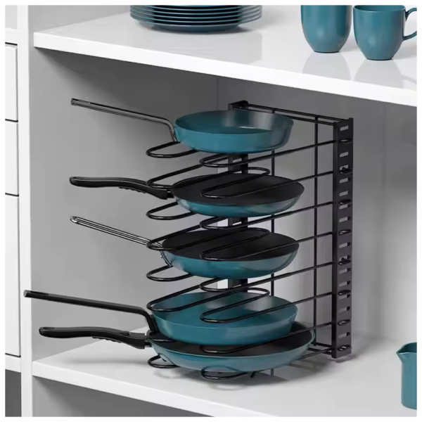 Compact metal pot rack organizing teal frying pans with black handles in a white kitchen cabinet